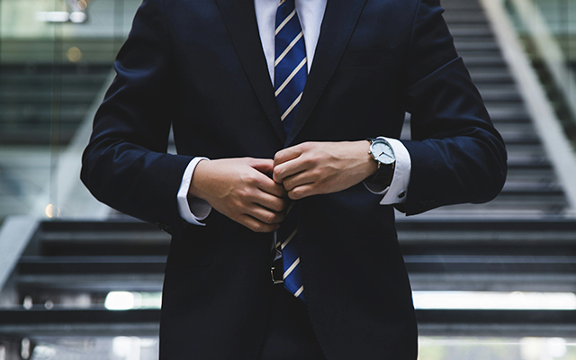 Employee closing up suit blazer walking outside building